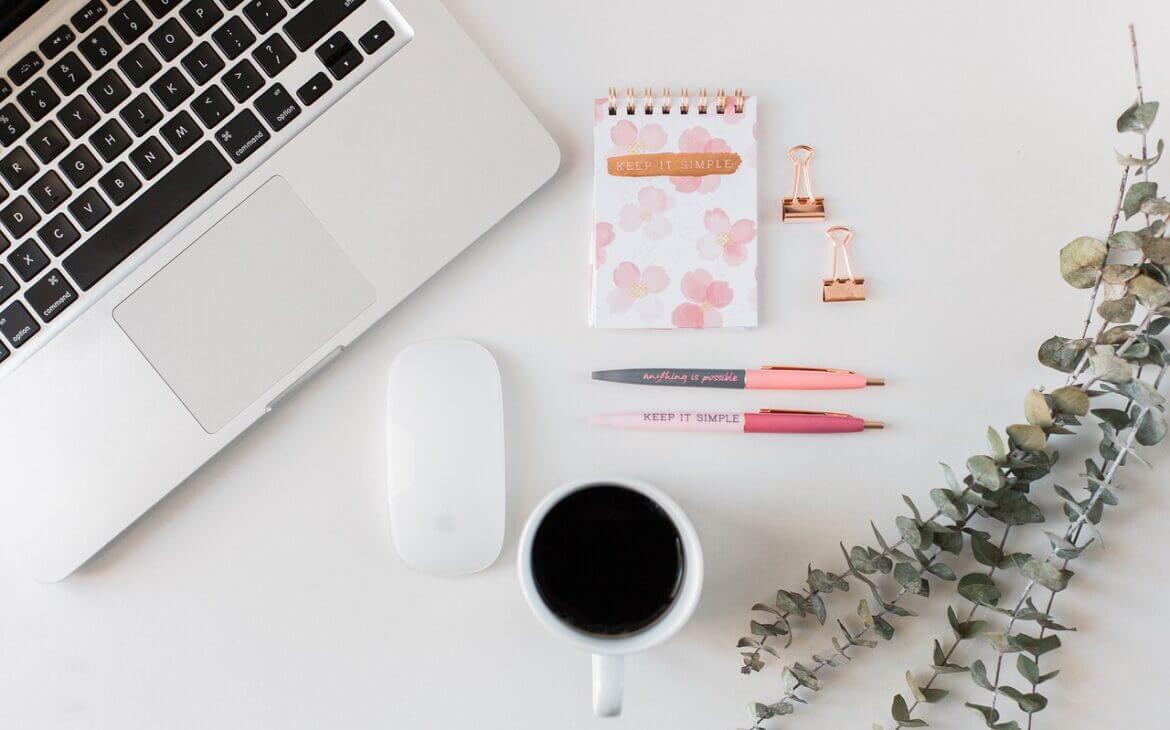 Organised desk with coffee, laptop and stationary